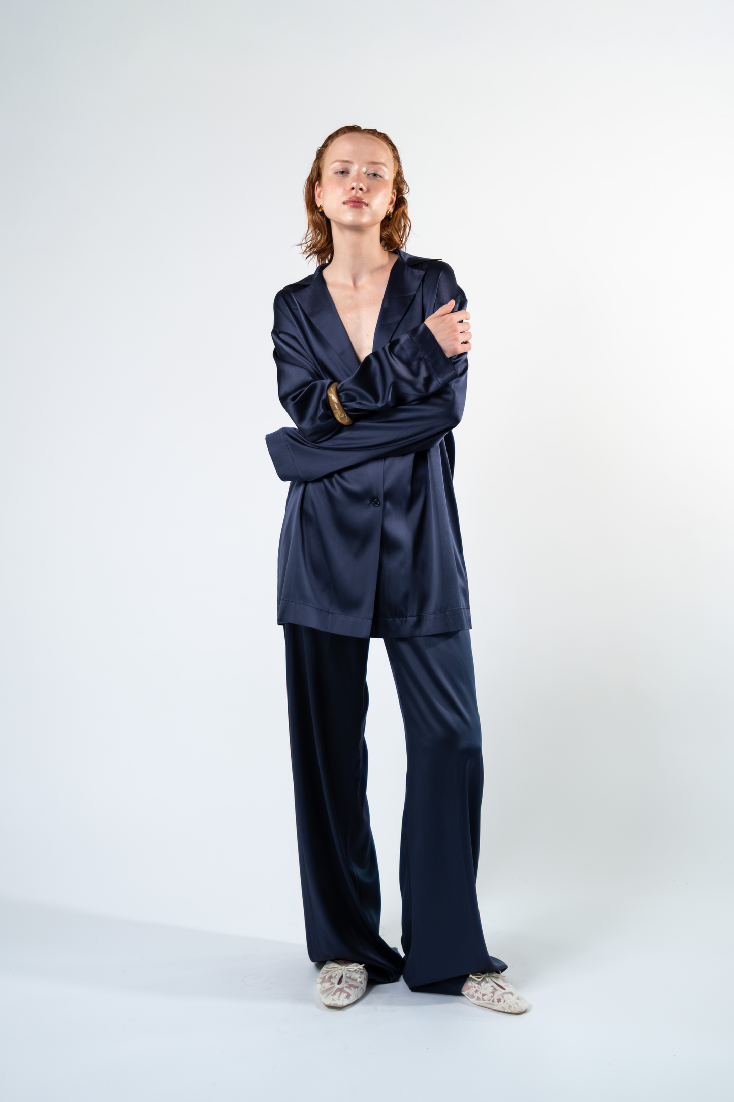 Vista frontale della camicia oversize in satin di seta blu con rever, taschino applicato e chiusura con tre bottoni. La silhouette lunga e morbida valorizza la lucentezza e il drappeggio naturale del satin.